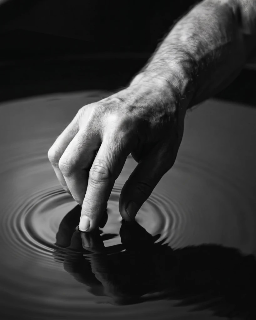 Nahaufnahme einer Hand, die eine Wasseroberfläche berührt
